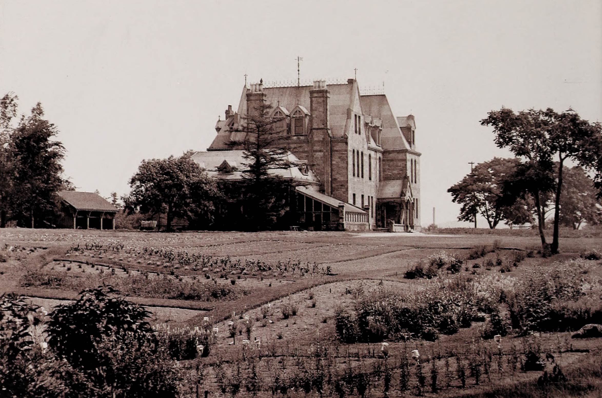 A sepia-tone photo of the building which housed the Bussey Institution of Harvard University.