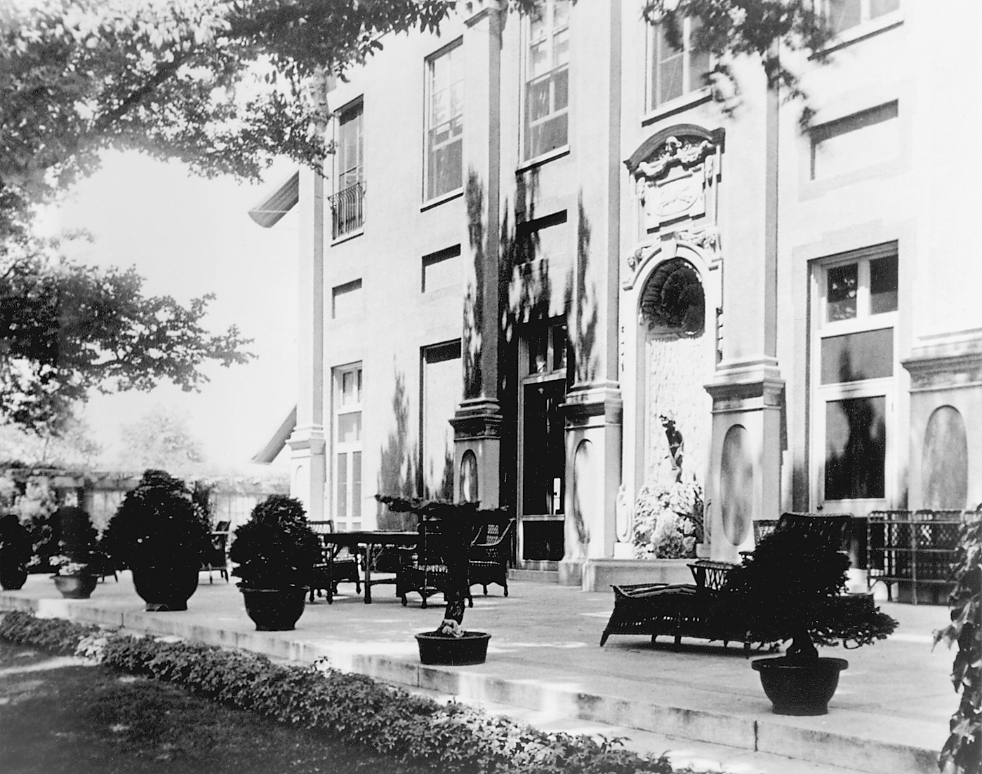 Black-and-white photograph showing bonsai lined along ornate patio