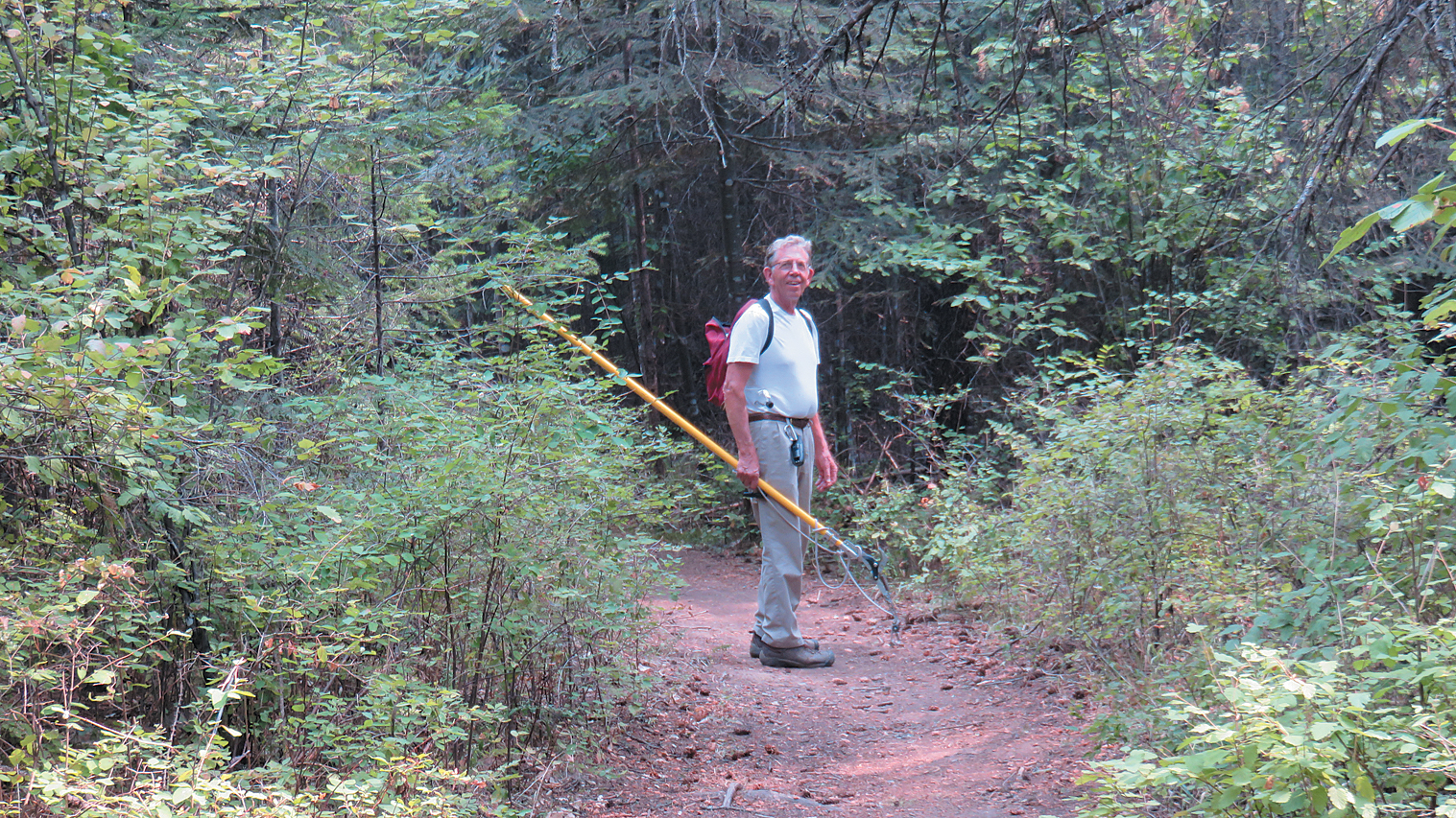 Photo of collector standing in path holding pole pruners