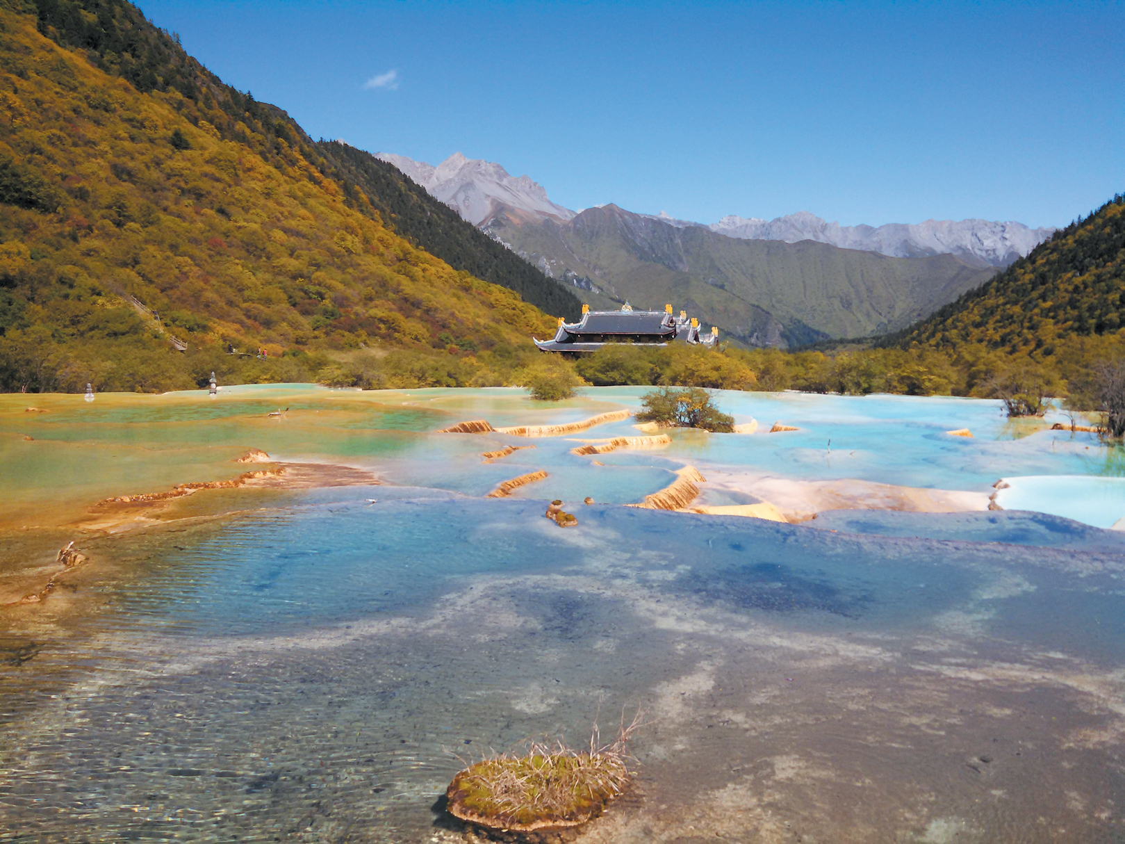 Dramatic orange and blue hot spring pools set within mountain valley