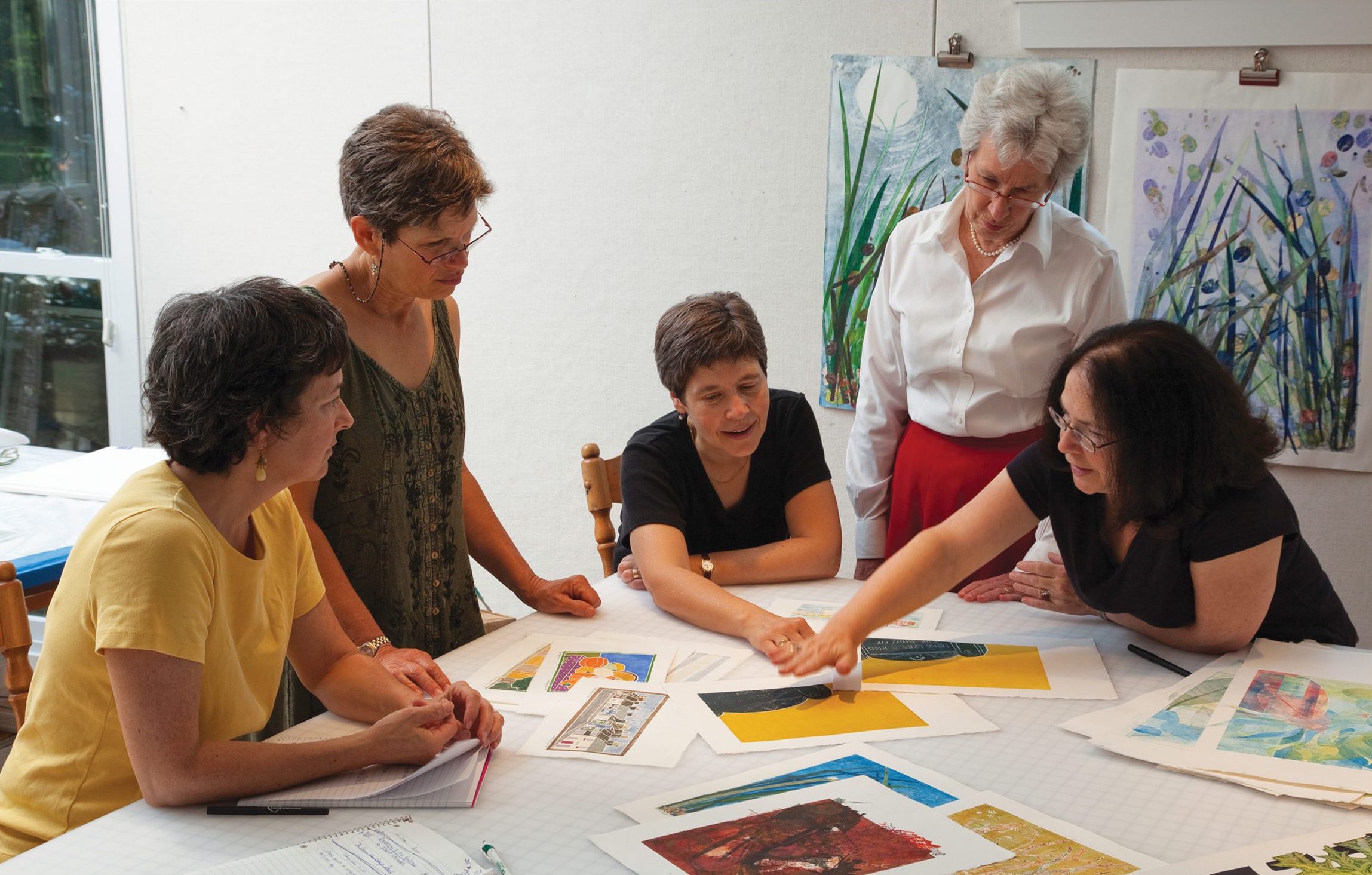 Photo of Amy McGregor-Radin, Lynda Goldberg, Gayle Smalley, Mary Beth Maisel, and Arlene Bandes looking at prints