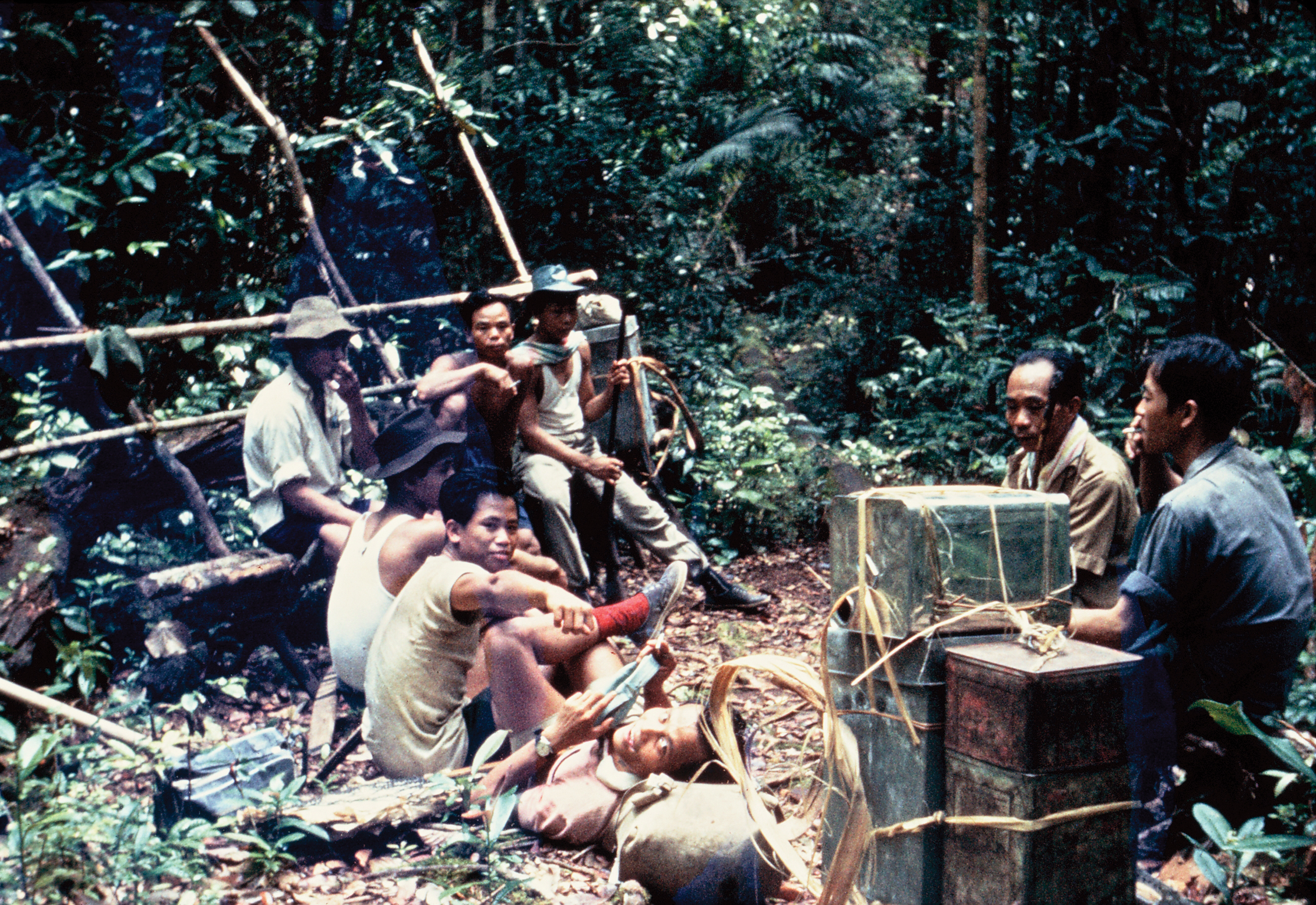 Recolored photograph of men sitting in camp