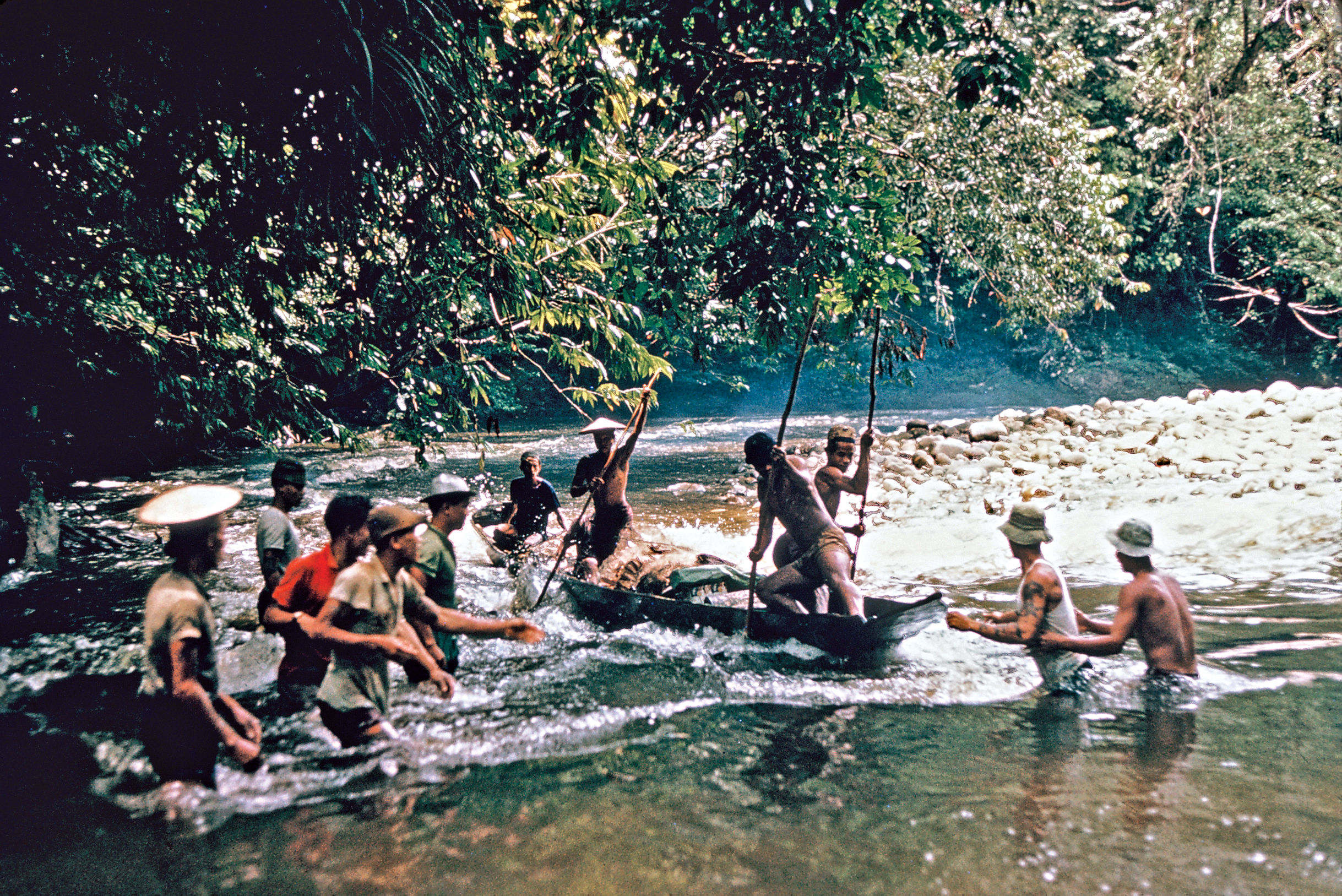 Color photograph of men navigating boat through river rapids