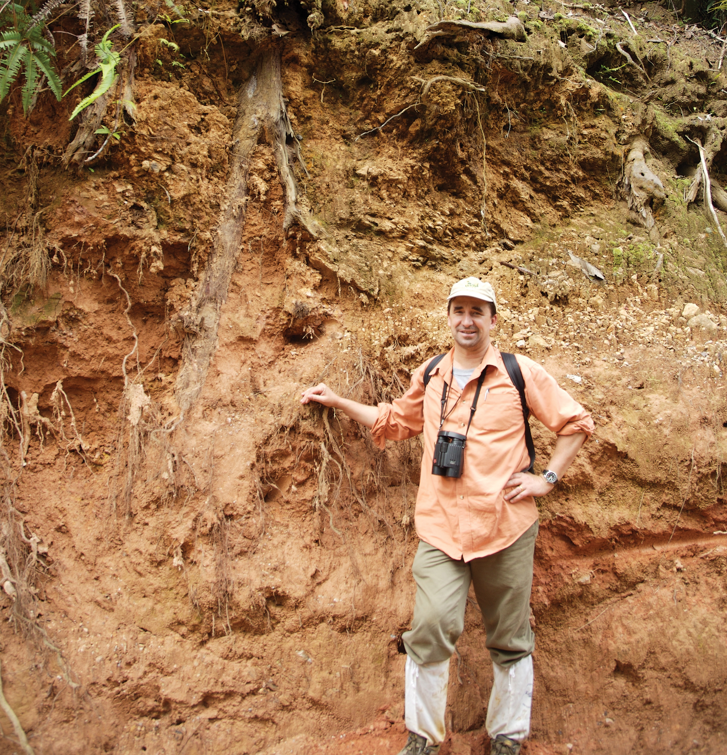 Color photograph of Stuart Davis standing in front of earth embankment