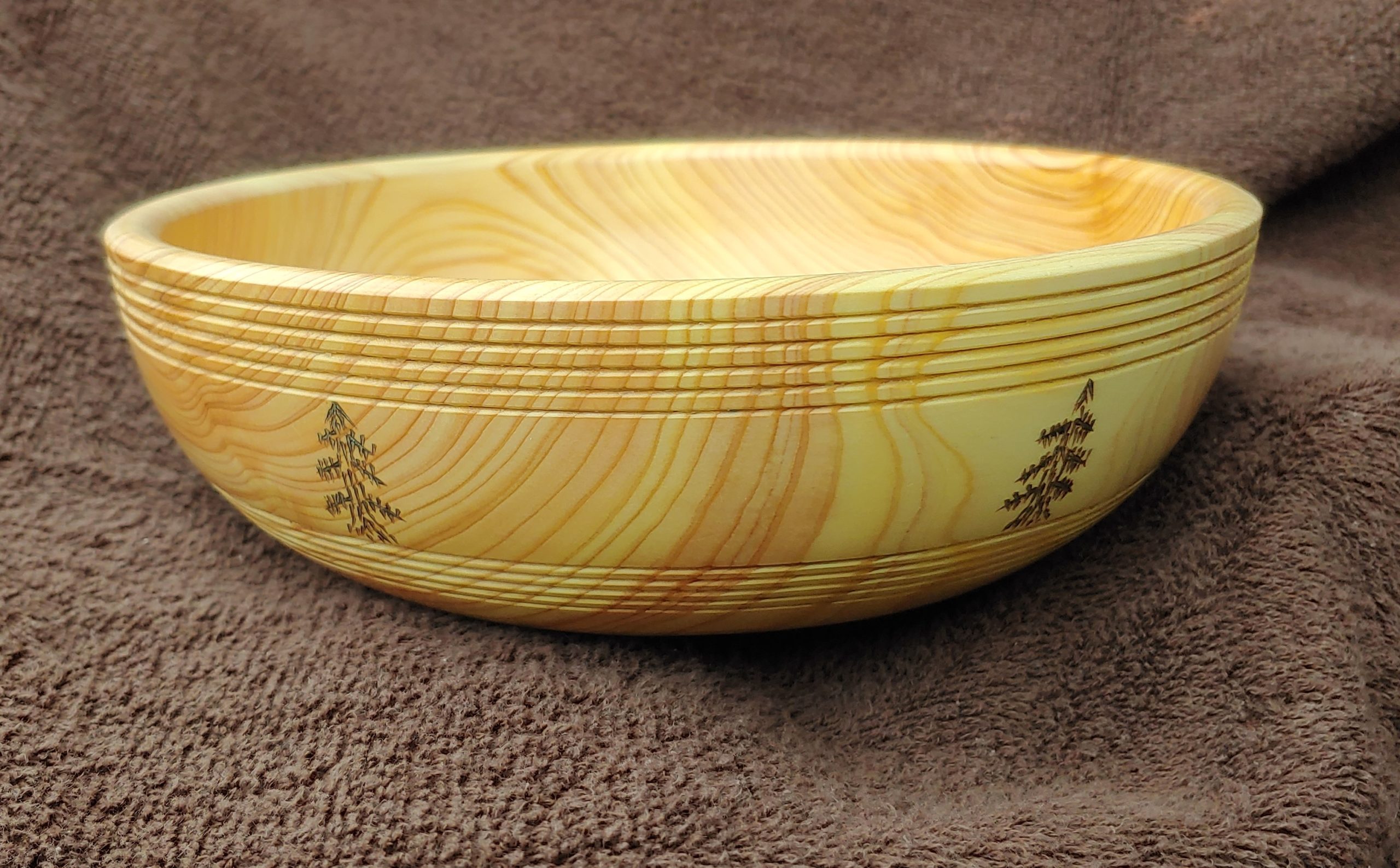 Shallow tuned wood bowl with tree etchings on side