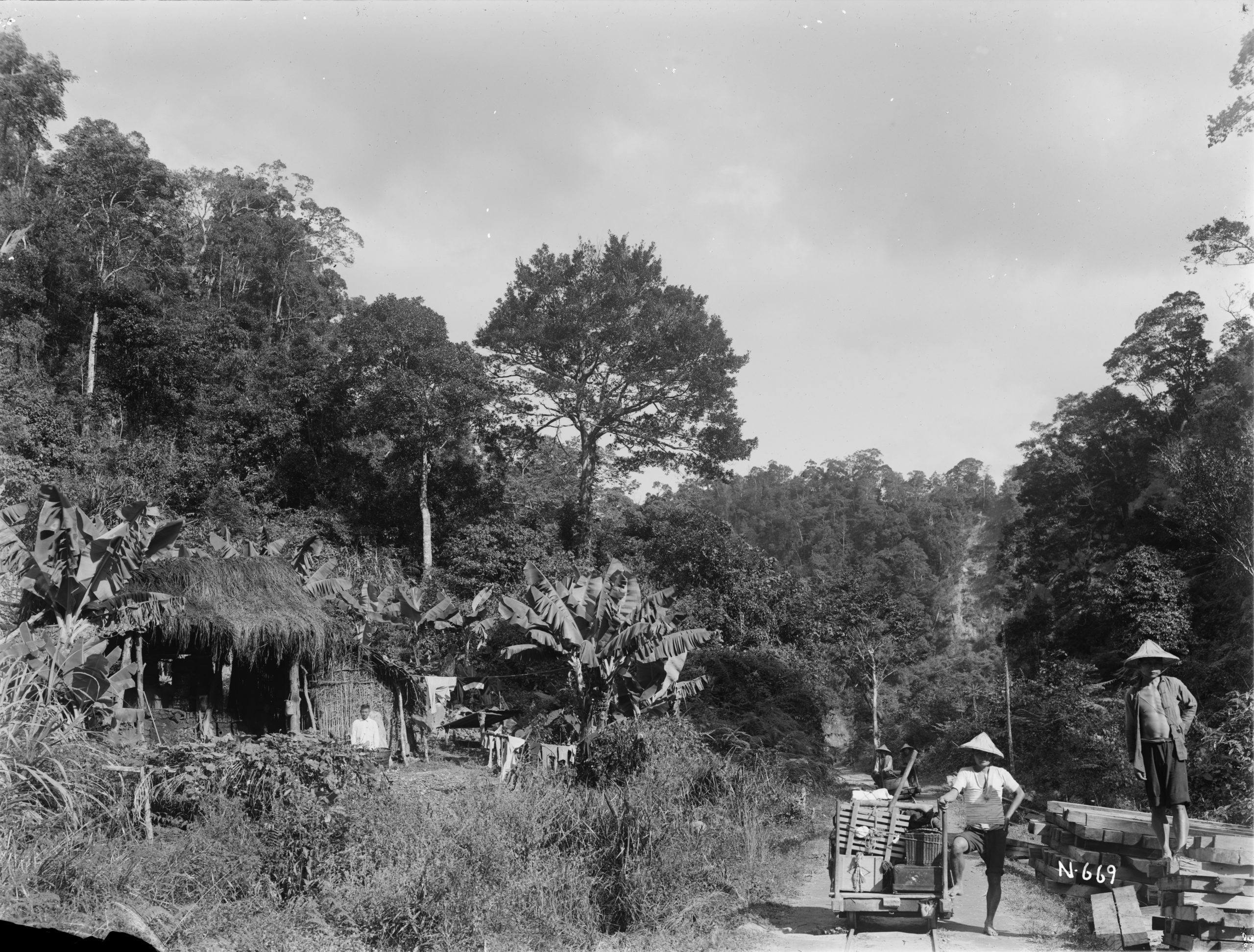 Two men stand beside a handcar running on tracks in this Ernest Wilson photograph from December 1918. There was a number of these vehicles running up into the mountains of Taiwan and Wilson made good use of them for hauling his equipment.