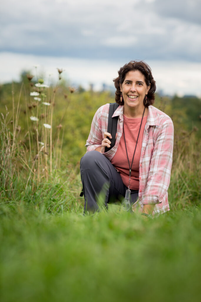 Ana Maria Caballero kneeling beside a plant.