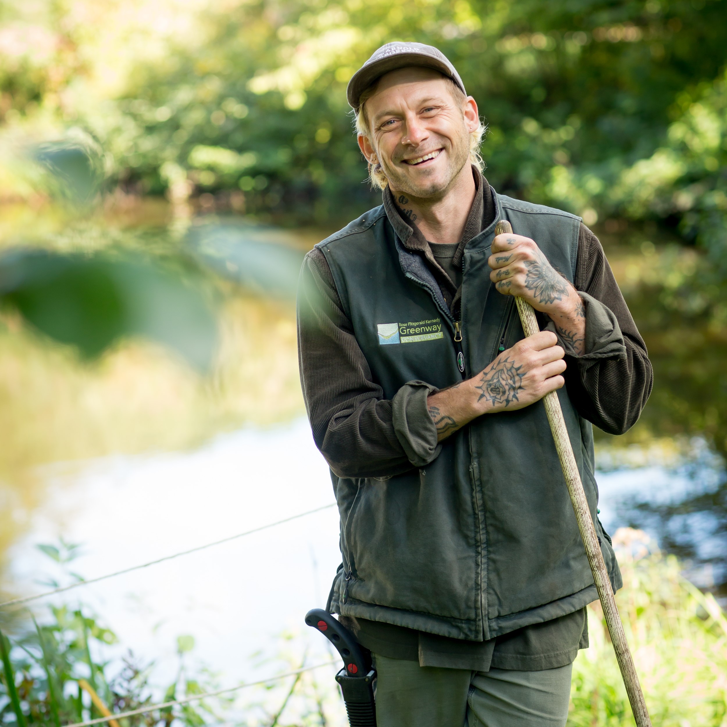 Horticulturist smiles standing in front of pond