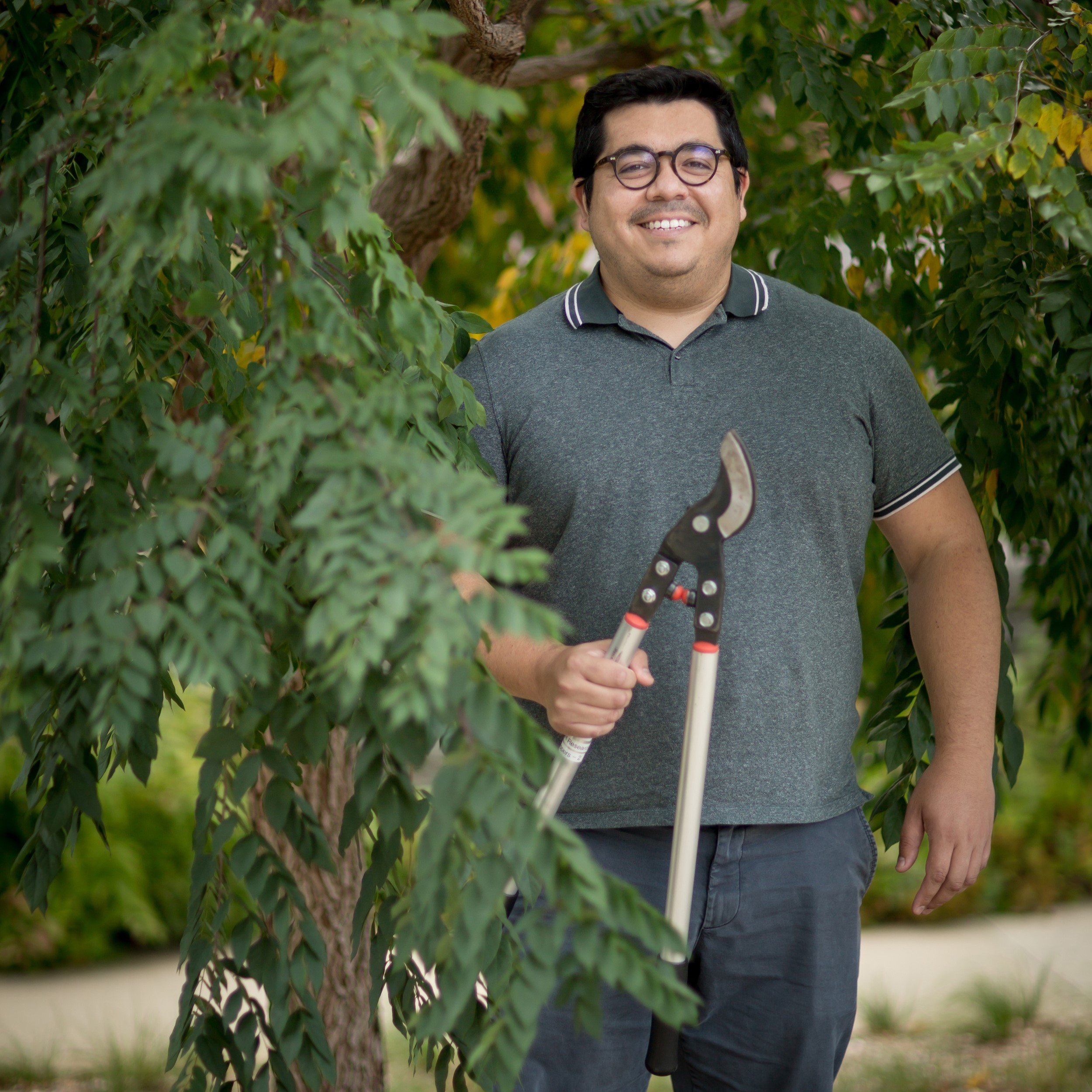 Man stands next to tree holding pruners