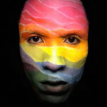 Man with his face painted artistically in rainbow colors