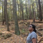 Woman with sunglasses looks up at the trees