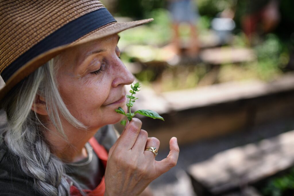 Woman in a hat smelling a small plant