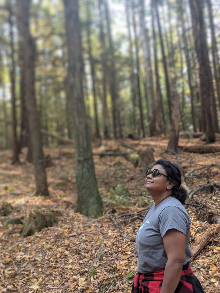 A woman looks up at the trees and smiles