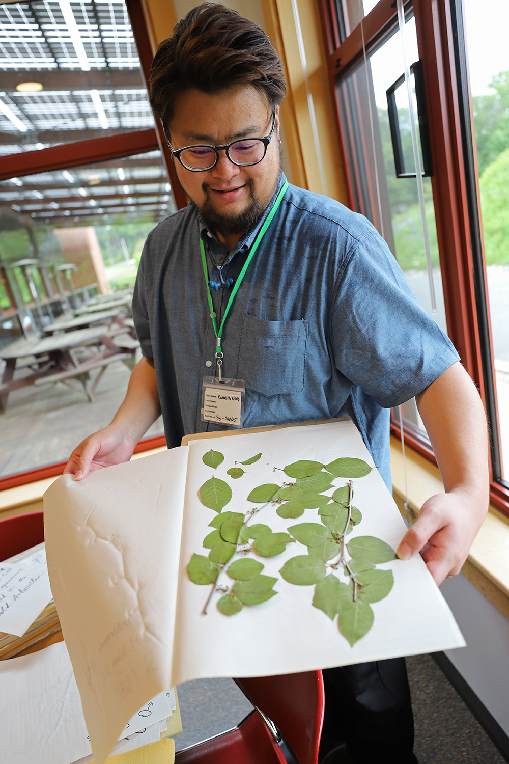 Researcher in blue shirt holds herbarium sample