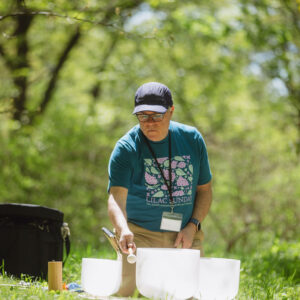 A man uses a crystal singing bowl in the woods