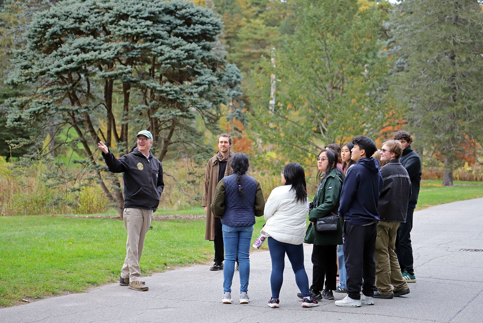 Group of people standing on road in front of green trees