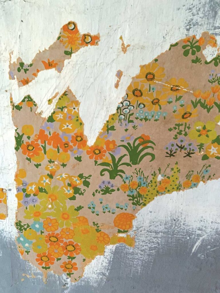 Wall with torn floral wallpaper, white and gray paint