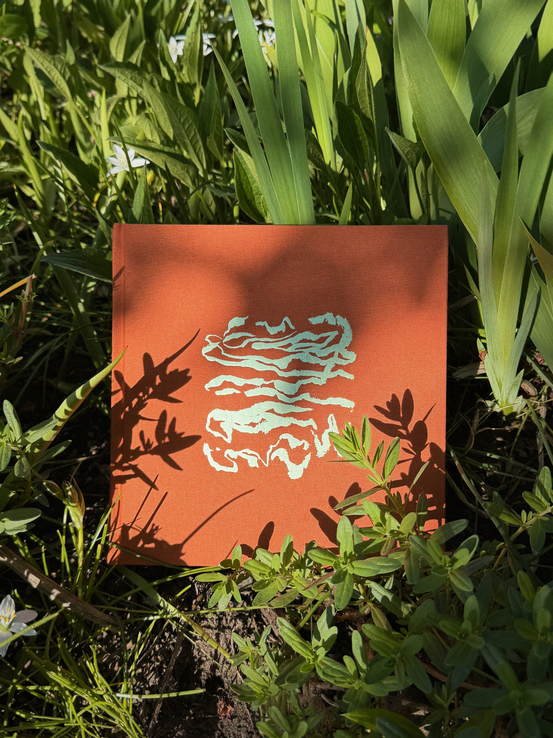 A hand-made book is pictured among a background of plants