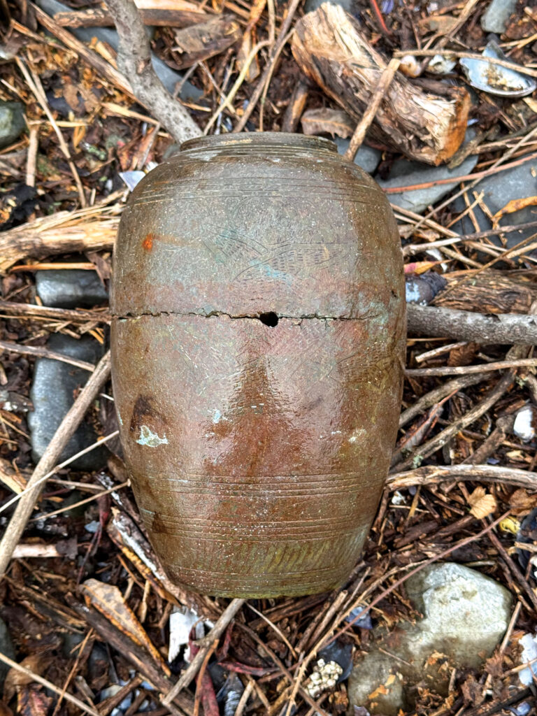 a cracked ceramic vase atop twigs and other debris
