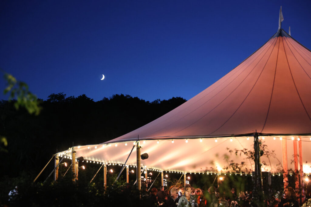 Large pink tent under a blue sky with green trees in the background